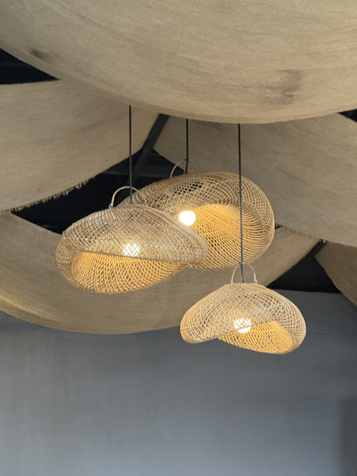 woven rattan pendant lights hanging from linen canopy